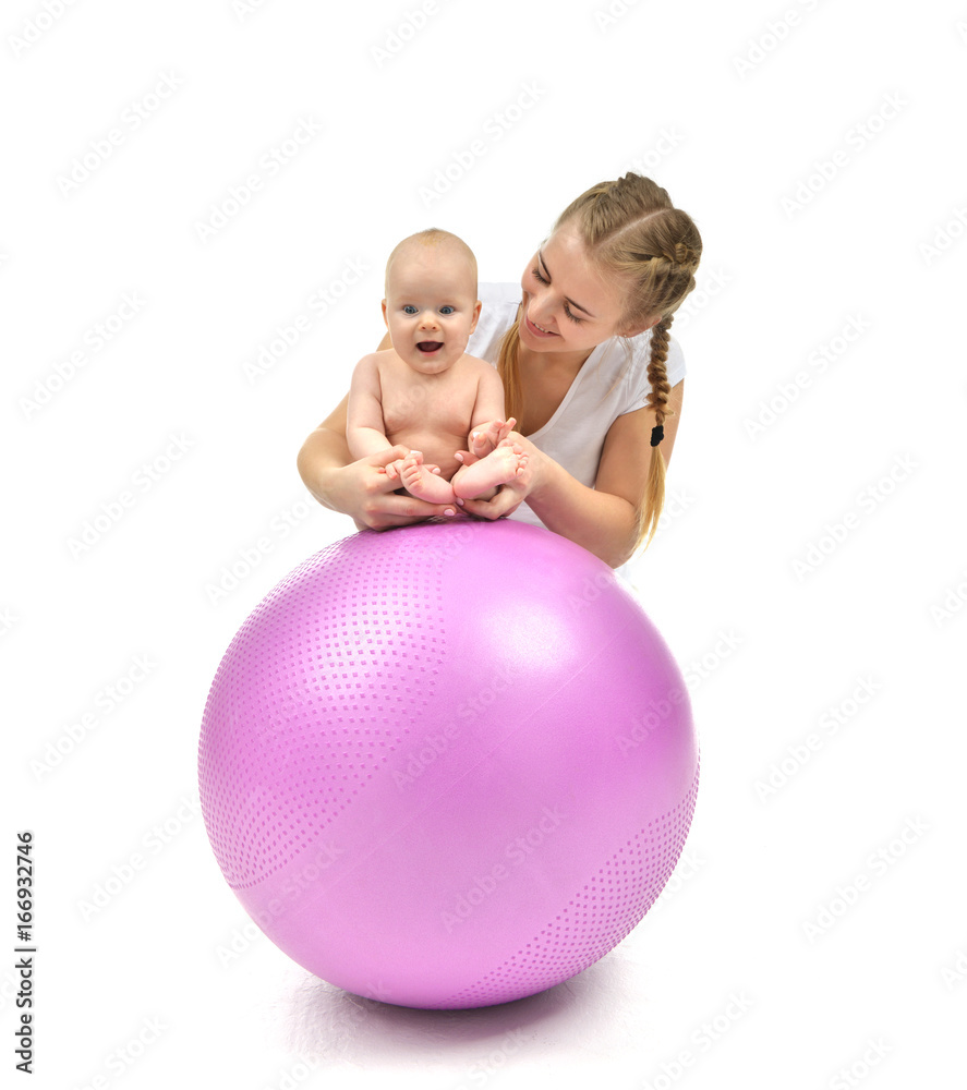 Happy mother make massage to her infant child baby on pink fitness ball Happy mother make massage to her infant child baby on pink fitness ball