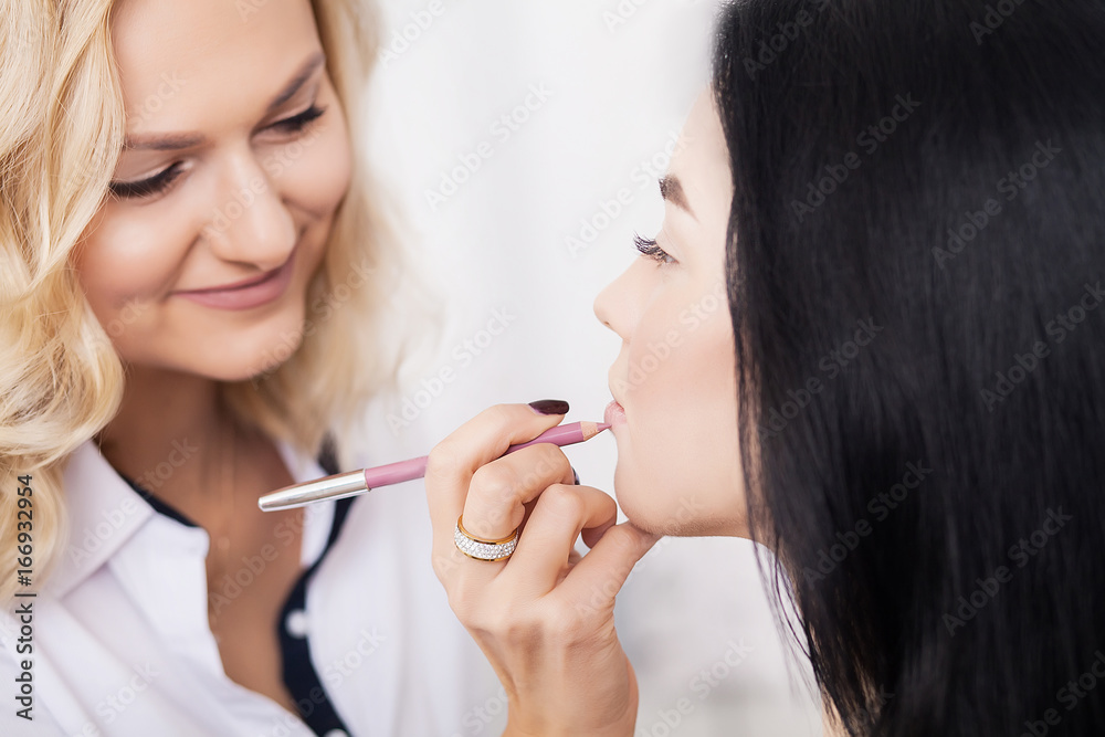 makeup artist applying lipstick on model lips with brush makeup artist applying lipstick on model lips with brush