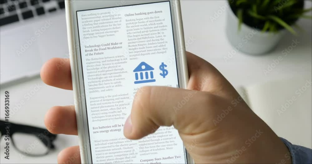 Man reading news on his smartphone sitting at his desk