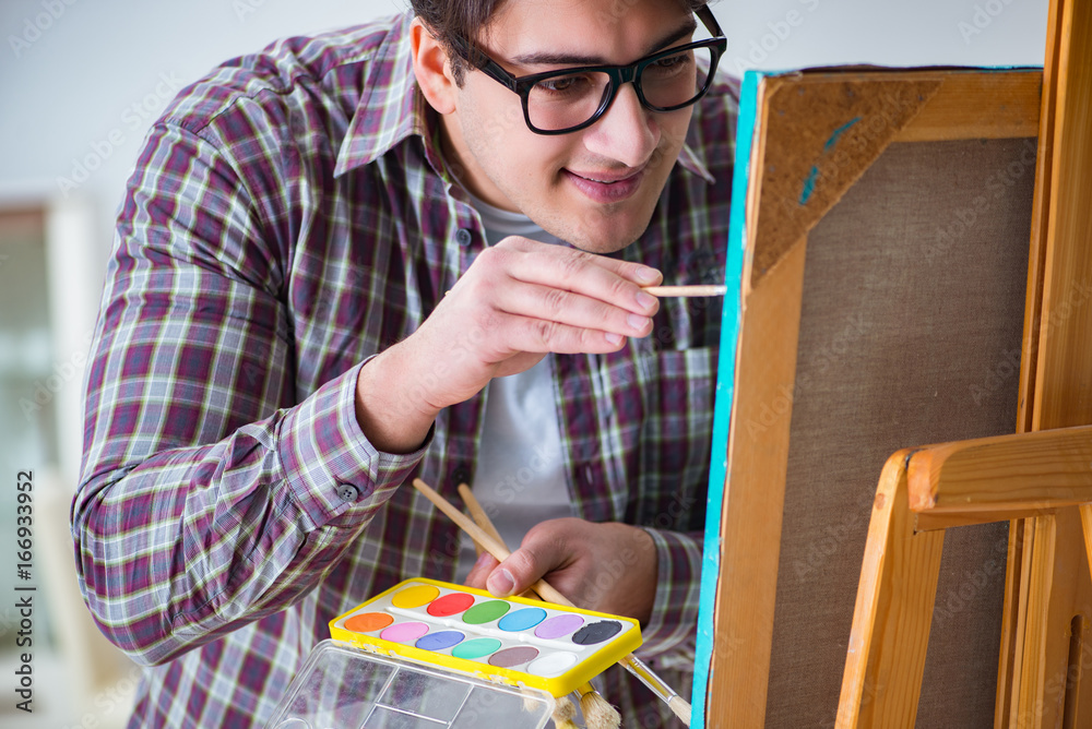 Young male artist drawing pictures in bright studio Young male artist drawing pictures in bright studio