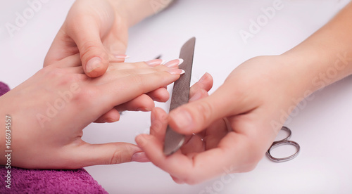 Closeup of four female hands. Professional manicurist doing nail polish.