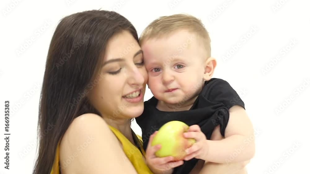 Mother kisses her baby, he laughs. White background. Slow motion