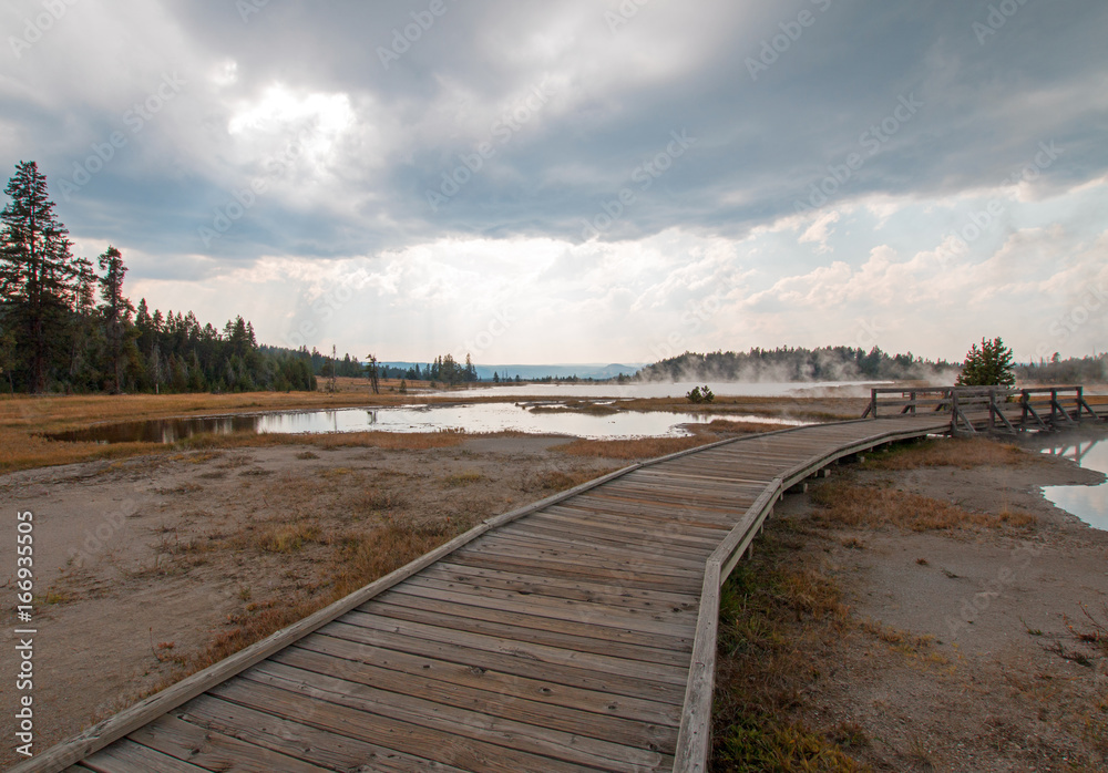 Curved Boardwalk next to Tangled Creek and Black Warrior Springs leading into Hot Lake in the Lower Geyser Basin in Yellowstone National Park in Wyoming United States