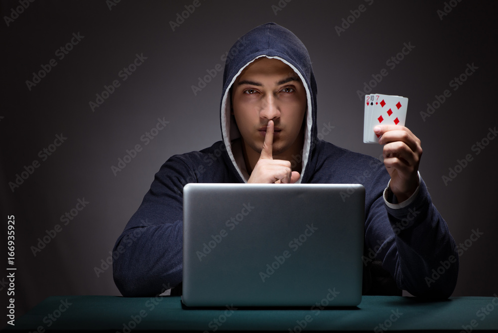 Young man wearing a hoodie sitting in front of a laptop computer Young man wearing a hoodie sitting in front of a laptop computer