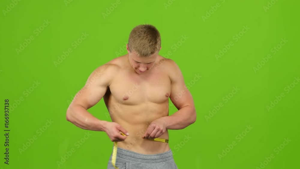 Male athlete measuring his press using ruler, green screen studio Male athlete measuring his press using ruler, green screen studio