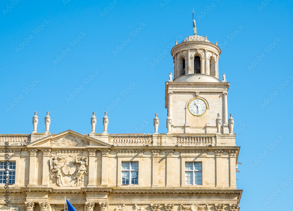 Clock tower of museum at center square of Arles, France, under clear blue sky