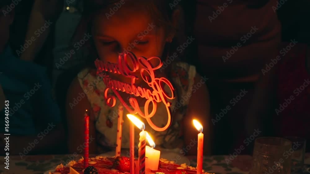 Cute little girl blowing out candles on a holiday cake in your birthday.