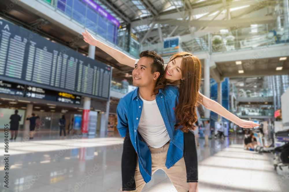 Happiness Asian couple traveler at the flight information screen in moddern an airport, lifestyle travel and transportation concept.