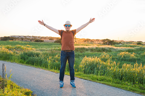 Man with arms raised, looking out over field
