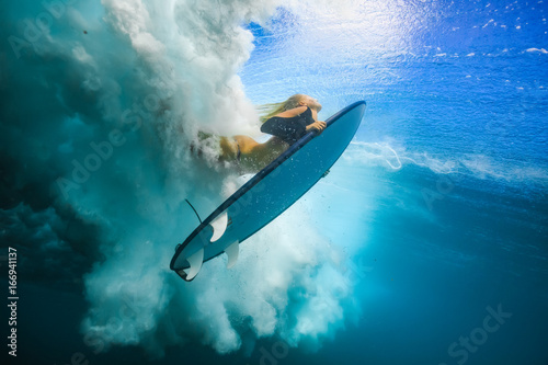 Photography Slim blonde girl in bikini a surfer with surf board duck diving underwater under ocean reflected surface