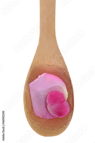 Rose water and rose pedals on a bamboo spoon.