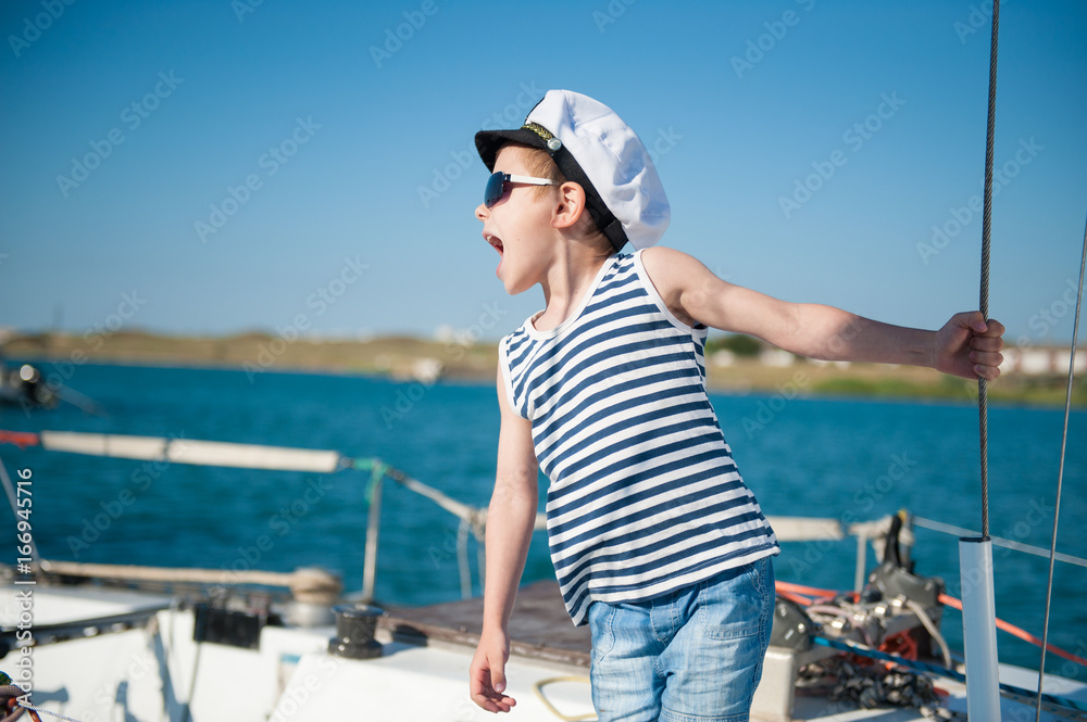 handsome little kid wearing sailor shirt and captain hat and sunglasses giving orders handsome little kid wearing sailor shirt and captain hat and sunglasses giving orders