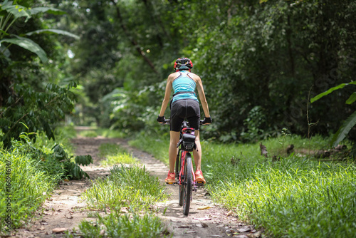 woman riding ahead on mountain bike in the rainforest adventure