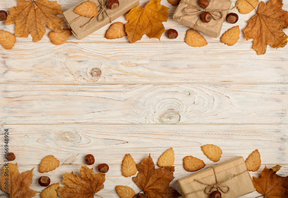 Flat lay frame of yellow leaves, cookies in the form of leaves, hazelnuts and gift boxes on a light wooden background. Flat lay frame of yellow leaves, cookies in the form of leaves, hazelnuts and gift boxes on a light wooden background.