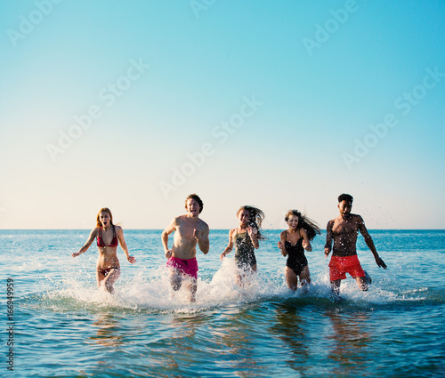 Group of friends run in the sea. Concept of summertime