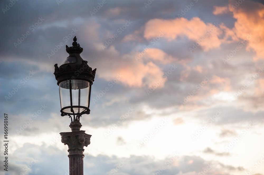 Parisian lamppost against clouds at sunset, France