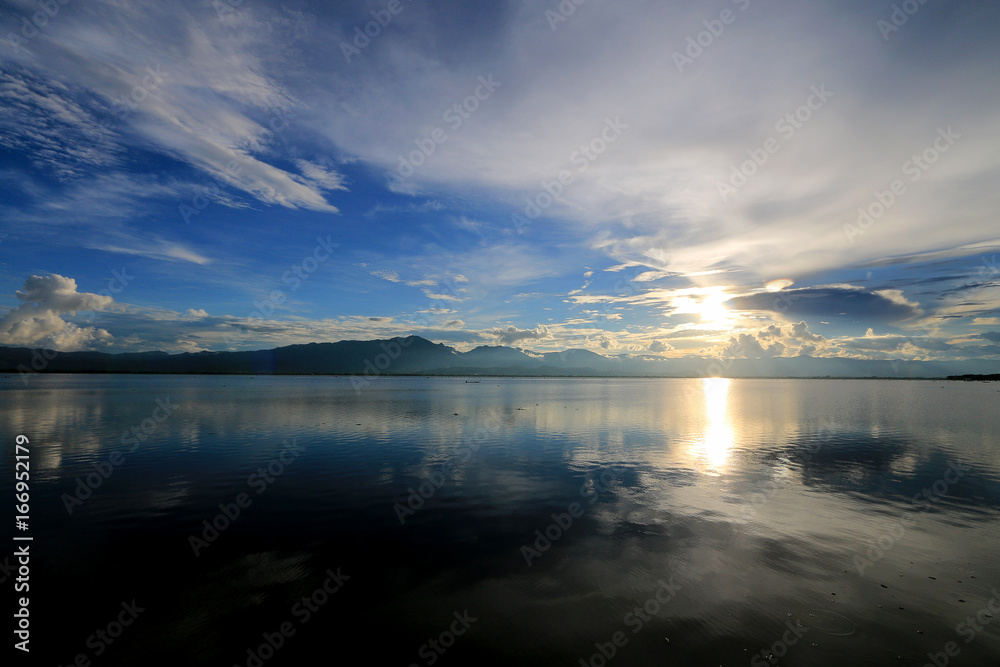 Beautiful sunset and evening sky with mountain and clouds and sunset reflected in the lake for background. Countryside Landscape Under Scenic Colorful Sky At Sunset Dawn Sunrise.