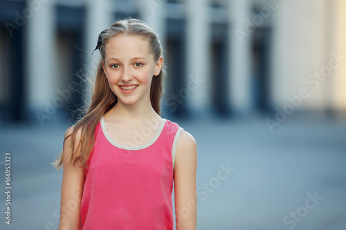 Young beautiful woman visiting a city center during a sunny day, smiling at the camera with buildings in the background. Free Download Young beautiful woman visiting a city center during a sunny day, smiling at the camera with buildings in the background. - GFXLoad