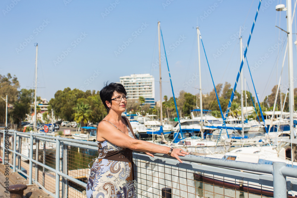 Leisure woman on holiday near yacht and sailboats marina resort town. Luxury lifestyle.