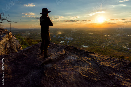 Man on the top of a rock to face the sunrise - success concept