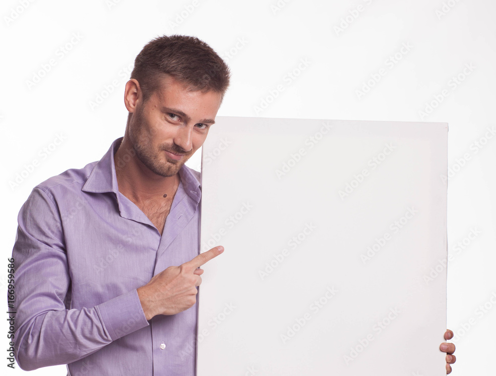 Young playful man portrait of a confident businessman showing presentation, pointing paper placard gray background. Ideal for banners, registration forms, presentation, landings, presenting concept. Young playful man portrait of a confident businessman showing presentation, pointing paper placard gray background. Ideal for banners, registration forms, presentation, landings, presenting concept.