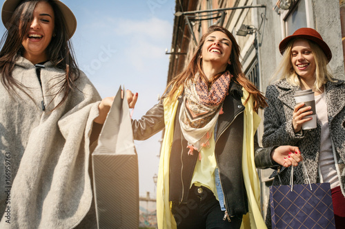 Three best friends walking on the street . Young female best friends doing shopping on the streets.