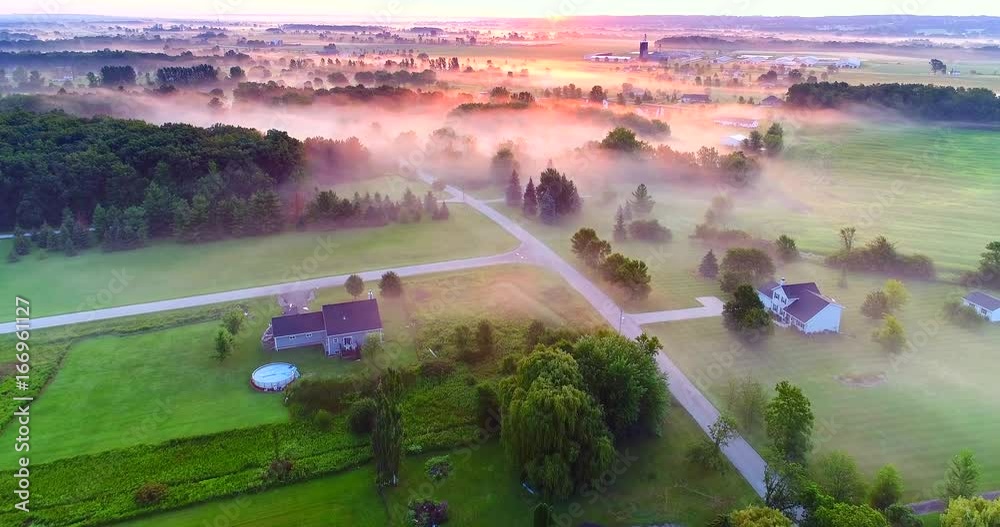 Ethereal foggy rural landscape at dawn, moving aerial view.
