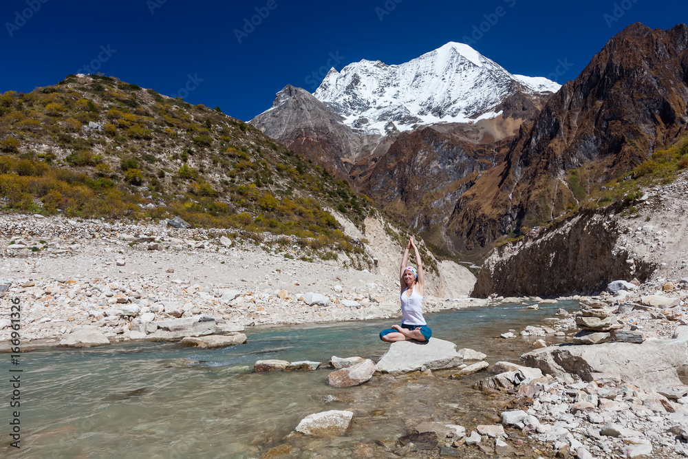 Fototapeta premium Woman is doing yoga excercises near big lake on the Manaslu circuit trak in Nepala