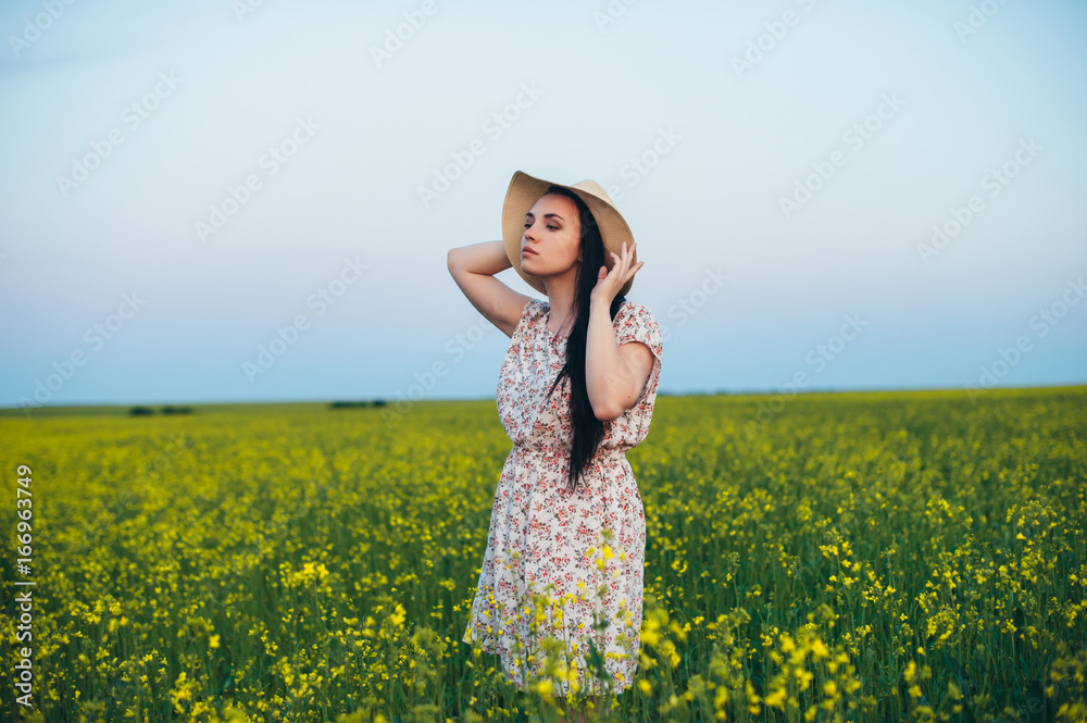 Fototapeta premium Beautiful young woman at sunset in the field