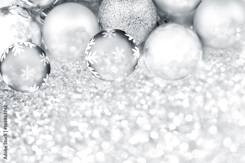 Silver Christmas balls on Silver glitter texture and defocused lights.