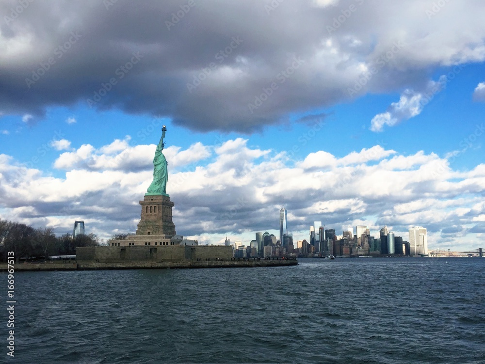 A side view of the Statue of Liberty with the Manhattan skyline in the back