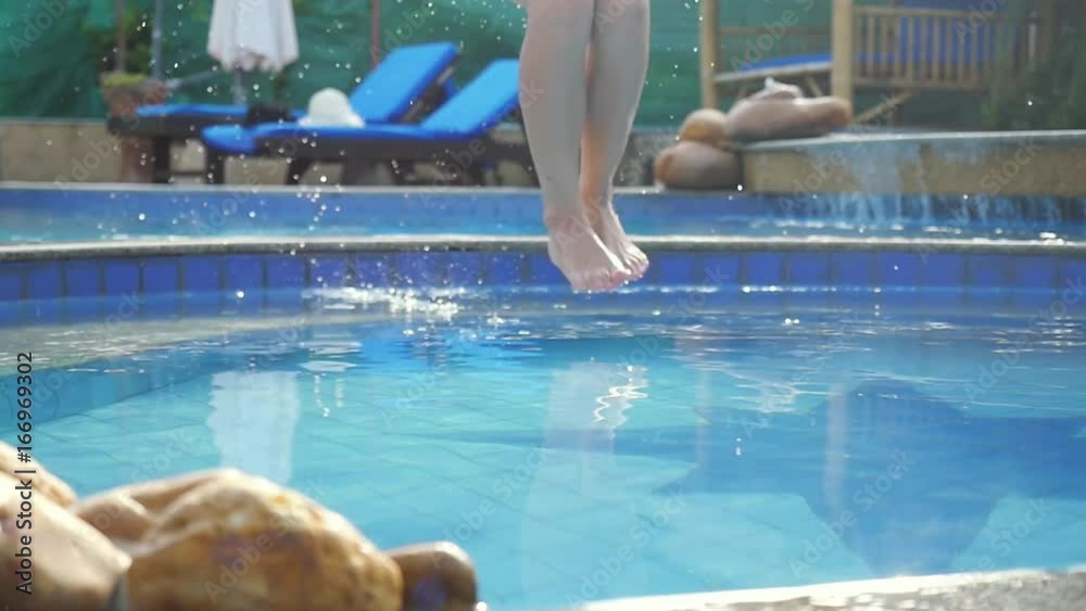 Young slim woman in pink bikini jumping into swimming pool in slow motion and water splashing on beautiful bokeh droplets. 1920x1080, hd