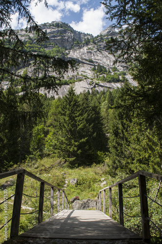 Italia: un ponte di legno sul percorso a piedi della Val di Mello, una valle verde circondata da montagne di granito e boschi, ribattezzata la Yosemite Valley italiana dagli amanti della natura