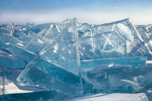 Transparent blue ice blocks on sky background in sunny frosty day, majestic winter landscape with hummocks