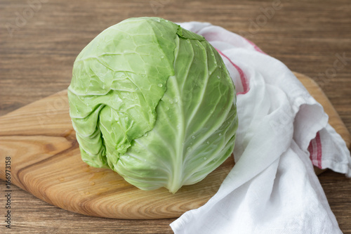 Fresh young cabbage on wooden board on wooden table  selective focus