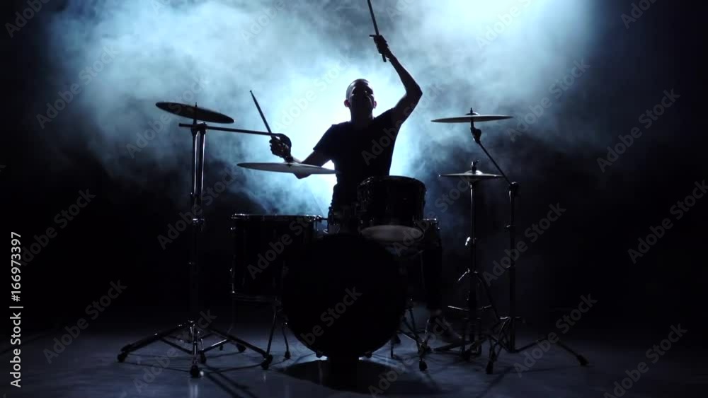 Drummer plays the melody on the drums energetically. Black background. Silhouette. Slow motion Drummer plays the melody on the drums energetically. Black background. Silhouette. Slow motion
