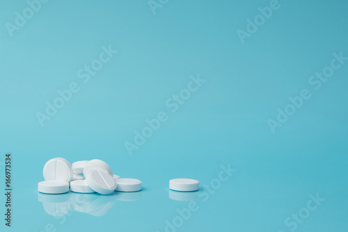White pills lie on a blue surface.Copy space photo