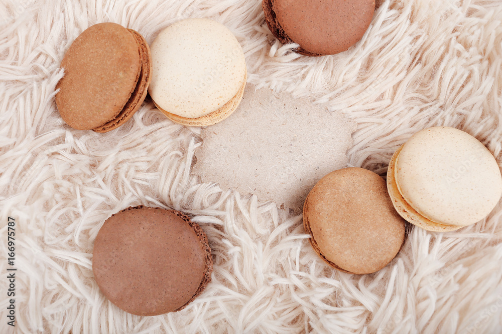 Macarons with paper blank copy space. Macarons of coffee color on a soft background, with a blank for a design. Macarons with paper blank copy space. Macarons of coffee color on a soft background, with a blank for a design.