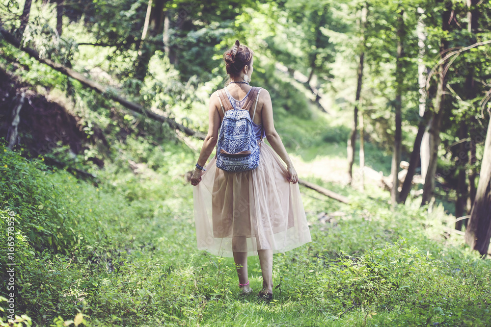 Fototapeta premium Girl walking away in the forest, enjoying nature
