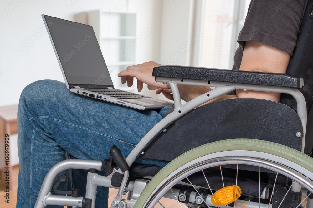 Handicapped disabled man on wheelchair is working with laptop in office. Handicapped disabled man on wheelchair is working with laptop in office.