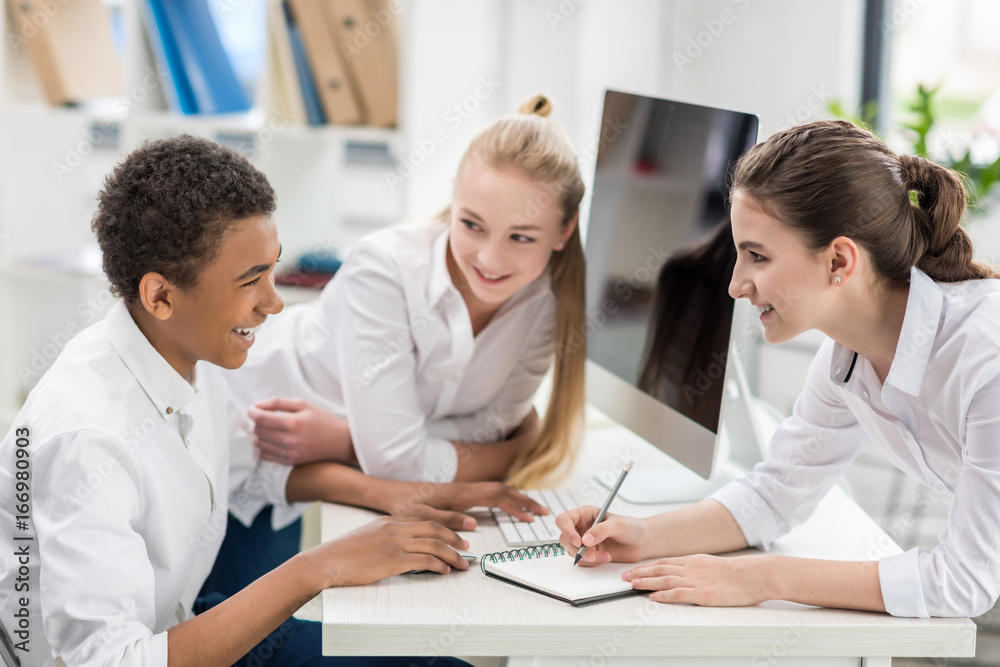 portrait of multicultural smiling students in white shirts working on project together portrait of multicultural smiling students in white shirts working on project together