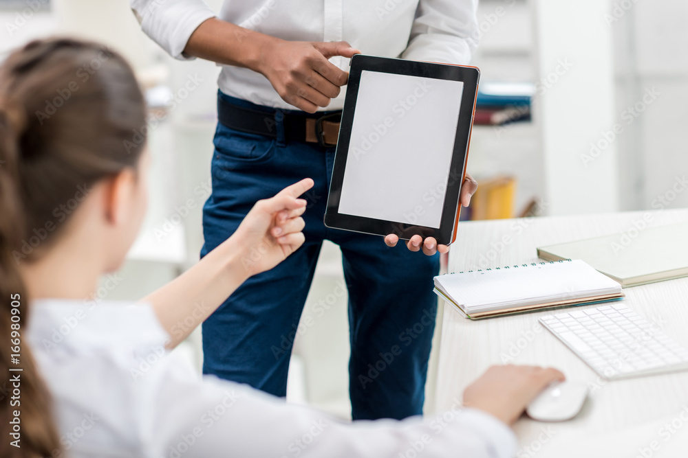 partial view of girl pointing at tablet blank screen in classmates hands in class partial view of girl pointing at tablet blank screen in classmates hands in class