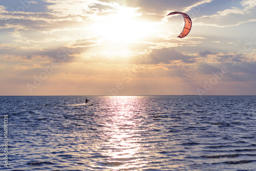 
An adult man is engaged in water sports (wakeboarding) at sea at sunset. Summer background. Free time, weekends and vacations  photo