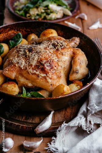 Whole roasted chicken with potatoes on dinner table