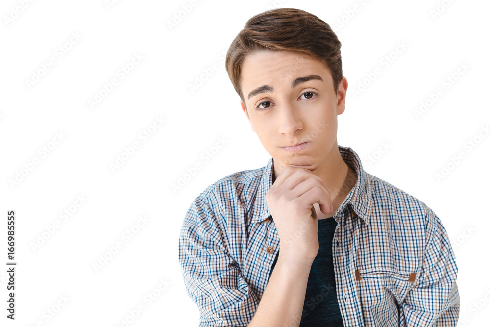 portrait of upset caucasian teenage boy with hand on chin looking at camera isolated on white portrait of upset caucasian teenage boy with hand on chin looking at camera isolated on white