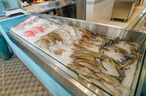Fresh line and pole caught fish and other seafoods,  in a bed of ice cubes, ready for sale in an industrial display.