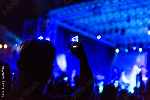 Hand with smartphone records live music festival, taking photo of concert stage live concert luxury party. Hand with smartphone records live music concert festival. Take photo in front of stage