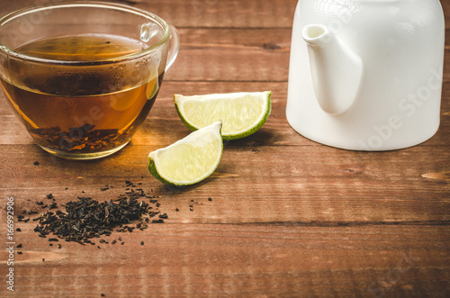 tea on a wooden table with a lime and a white teapot/tea with a lime and a white teapot
