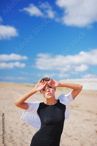 Emotional portrait of young sad woman in desperation lifted graceful hands and put his forehead looking at camera and detached gaze on wonderful background of summer blue sky and sandy beach, close-up