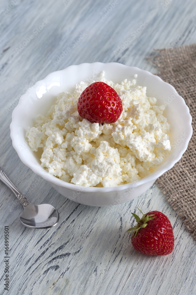 Cheese in white plate with one strawberry.